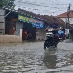 Warga melintas di genangan air banjir