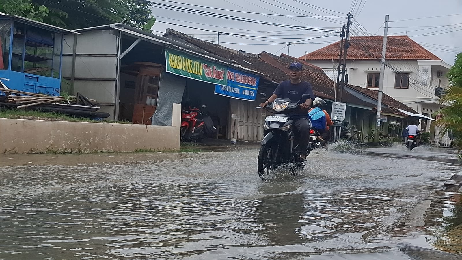 Warga melintas di genangan air banjir